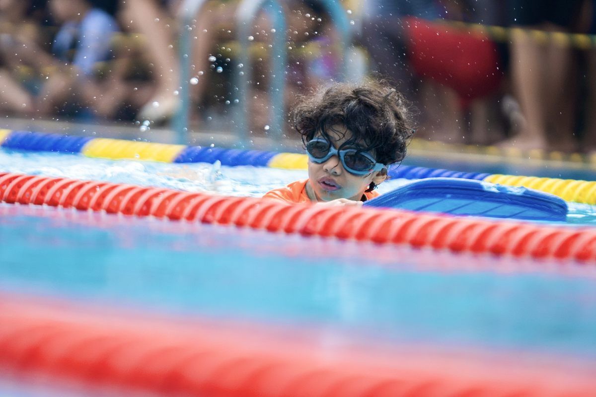 A young boy wearing goggles is swimming in a pool.
