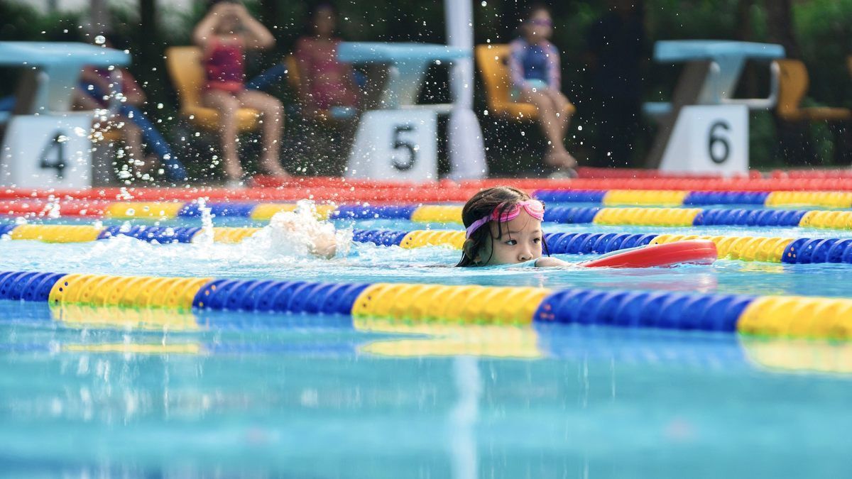 A young girl is swimming in a swimming pool.