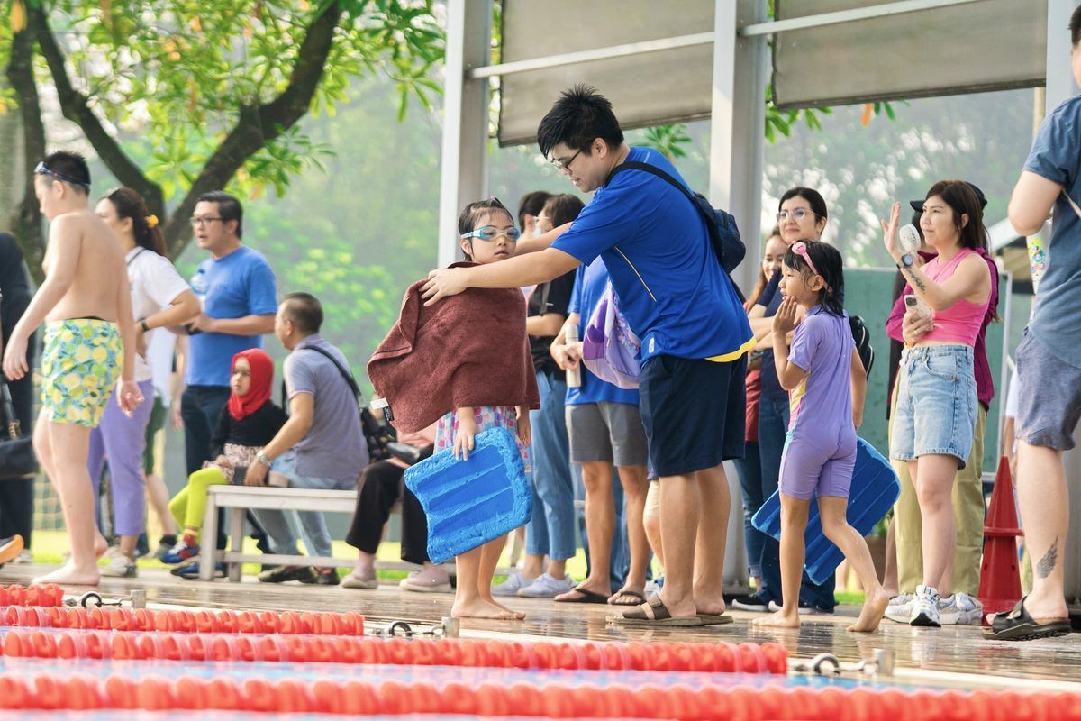 A group of people are standing around a swimming pool.