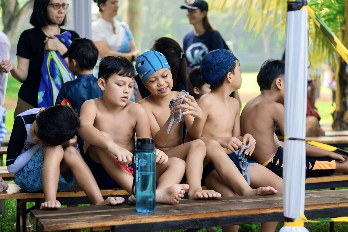 A group of children are sitting on a wooden bench.