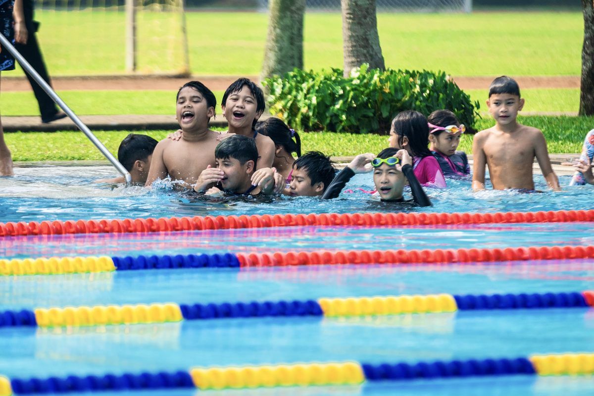A group of children are swimming in a swimming pool.
