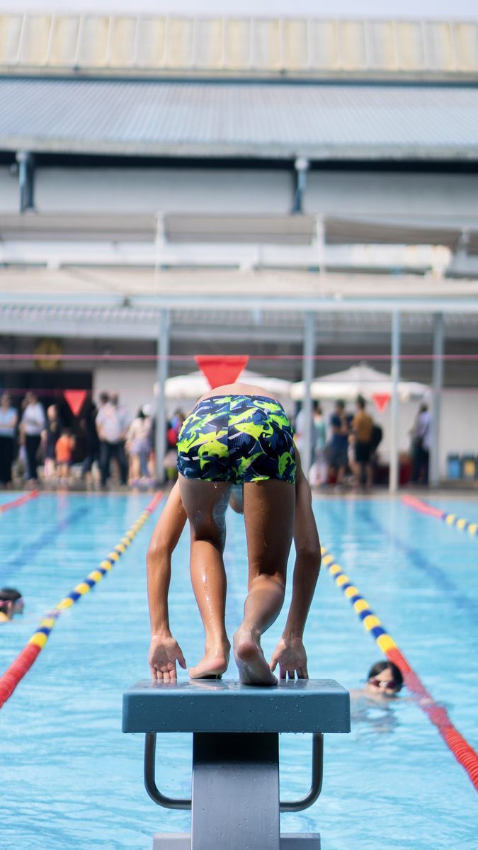 A young boy is getting ready to jump into a swimming pool.