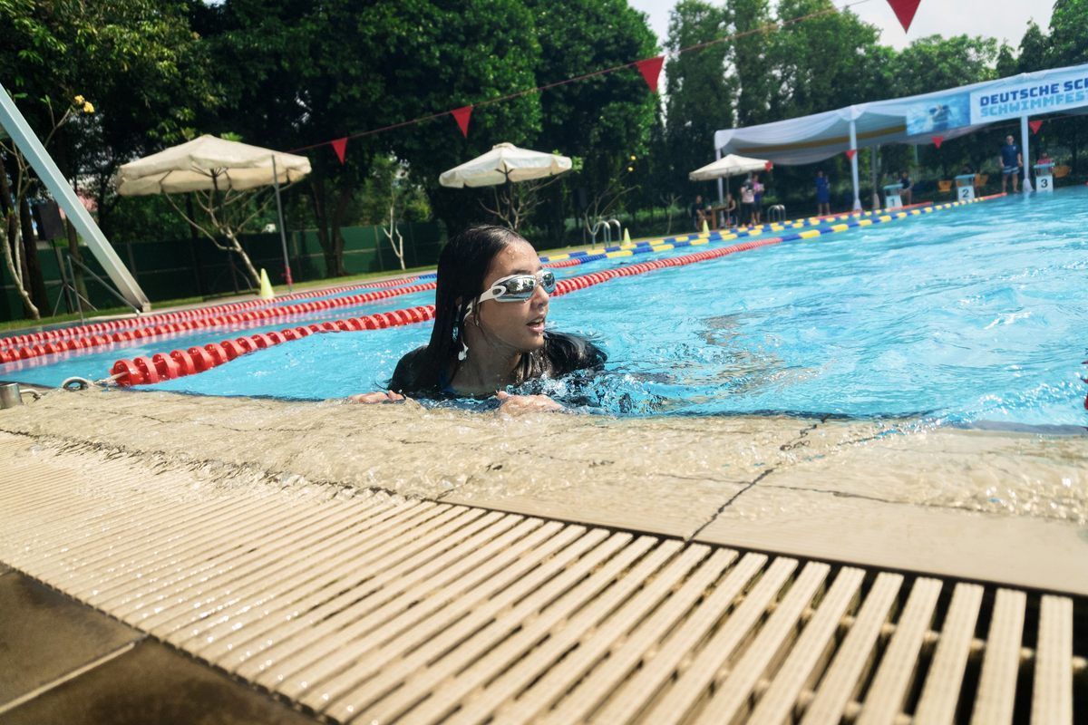 A woman is swimming in a swimming pool wearing goggles.