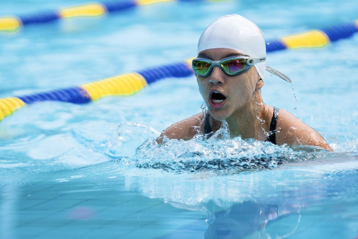A woman is swimming in a pool wearing a swim cap and goggles.