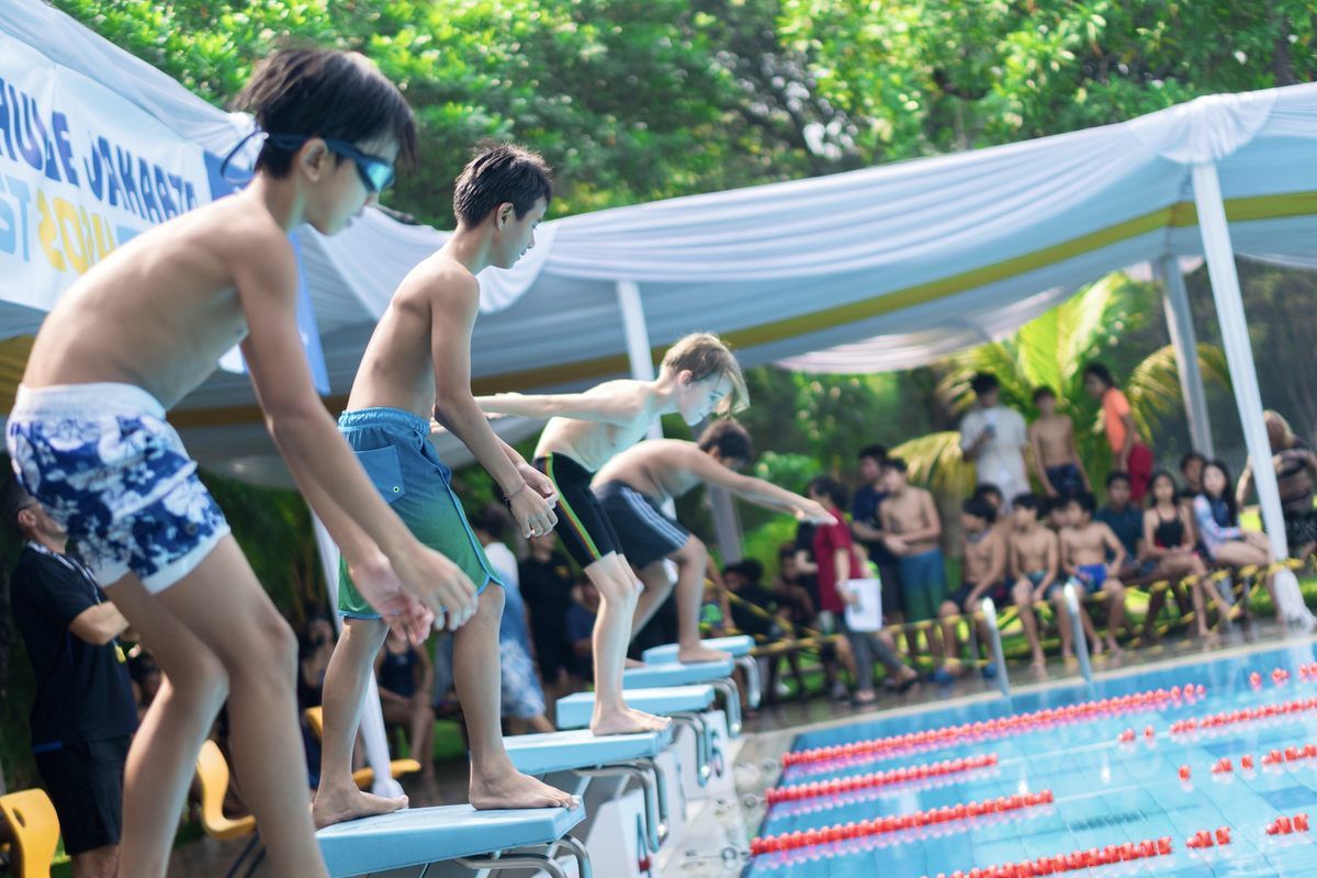 A group of young boys are jumping into a swimming pool.