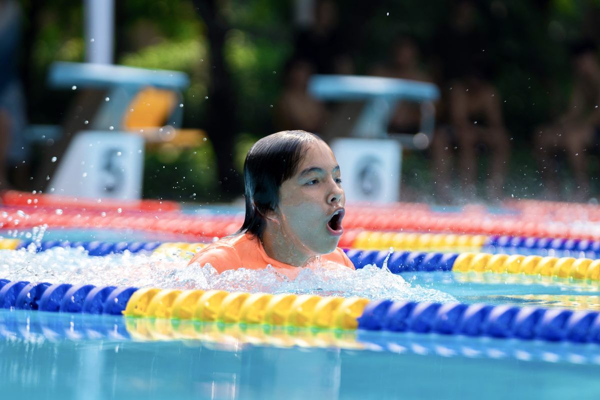 A young girl is swimming in a swimming pool.