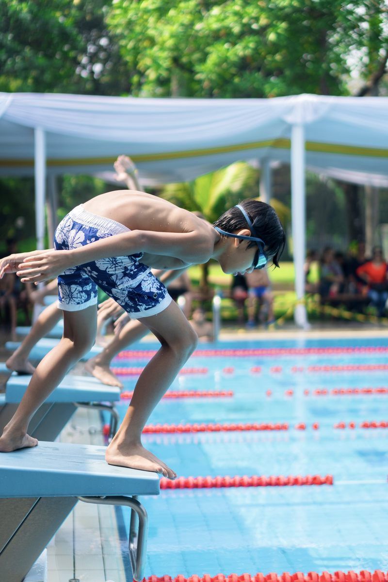 A group of young boys are jumping into a swimming pool.