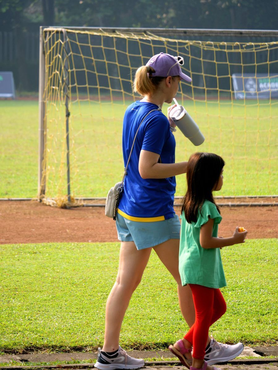 A woman and a little girl are walking on a field