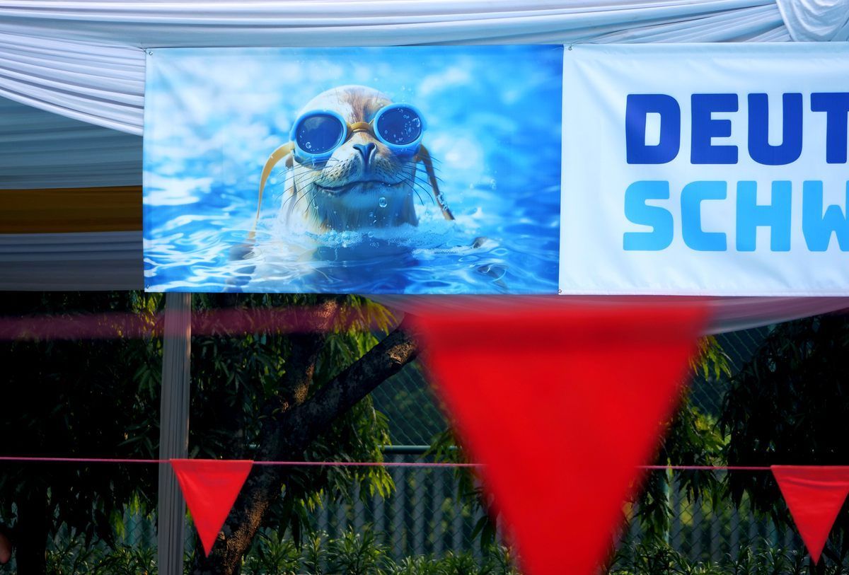 A sign with a picture of a dog wearing goggles says deutsch schwimm