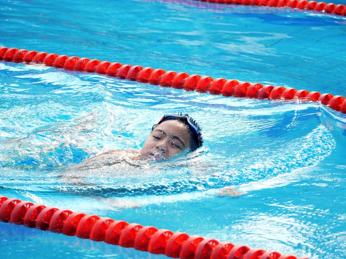 A young boy is swimming in a pool with red lanes.