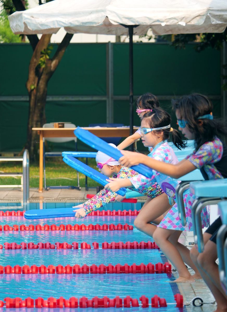 A group of young girls are getting ready to swim in a pool