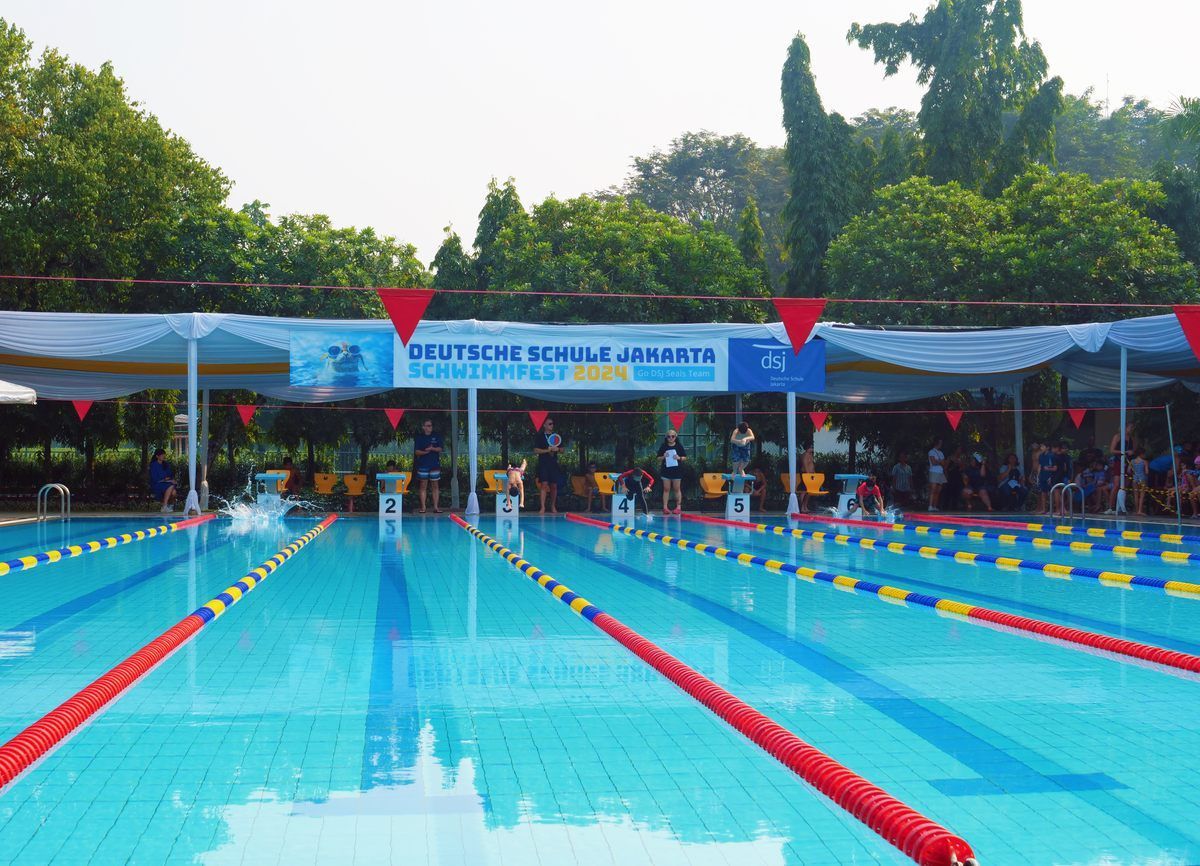 A large swimming pool with a sign that says ' deutsche schule juniors ' on it