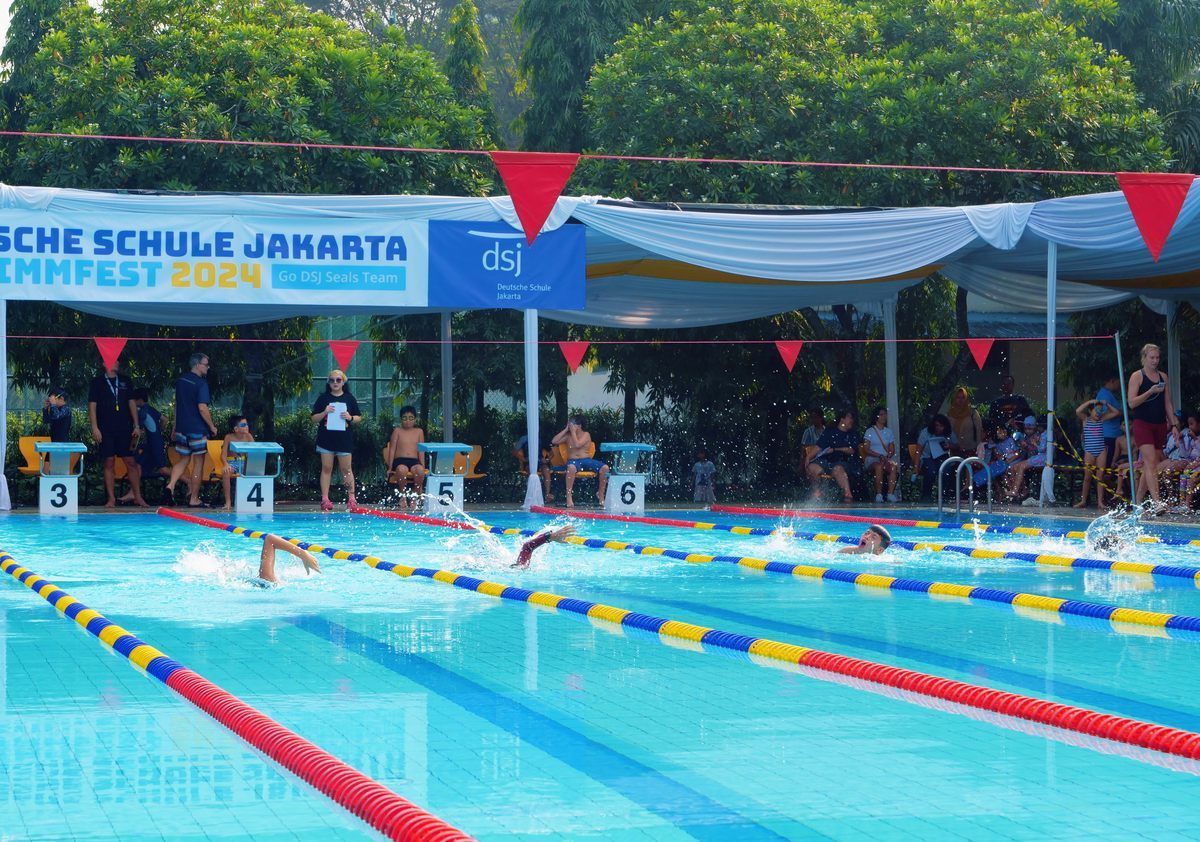 A group of people are swimming in a large swimming pool.