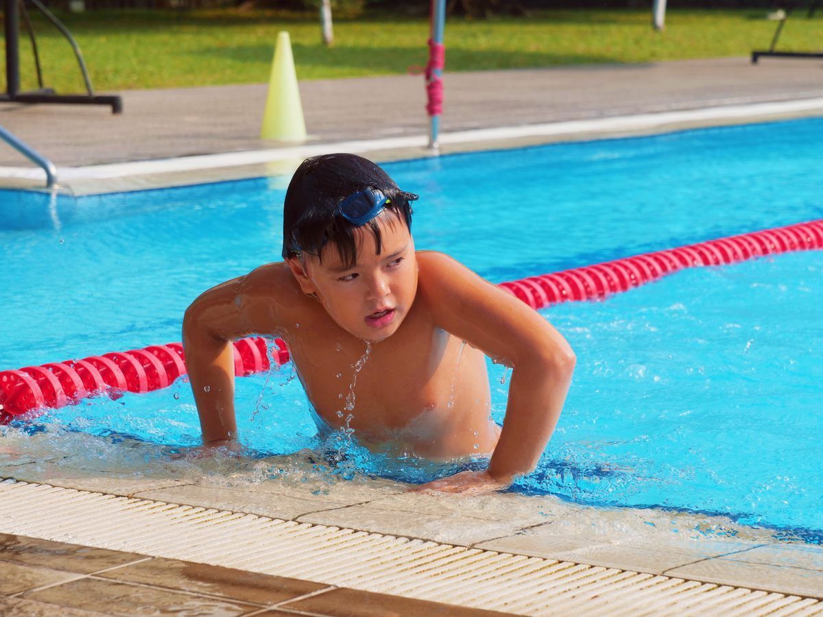 A young boy is swimming in a swimming pool.