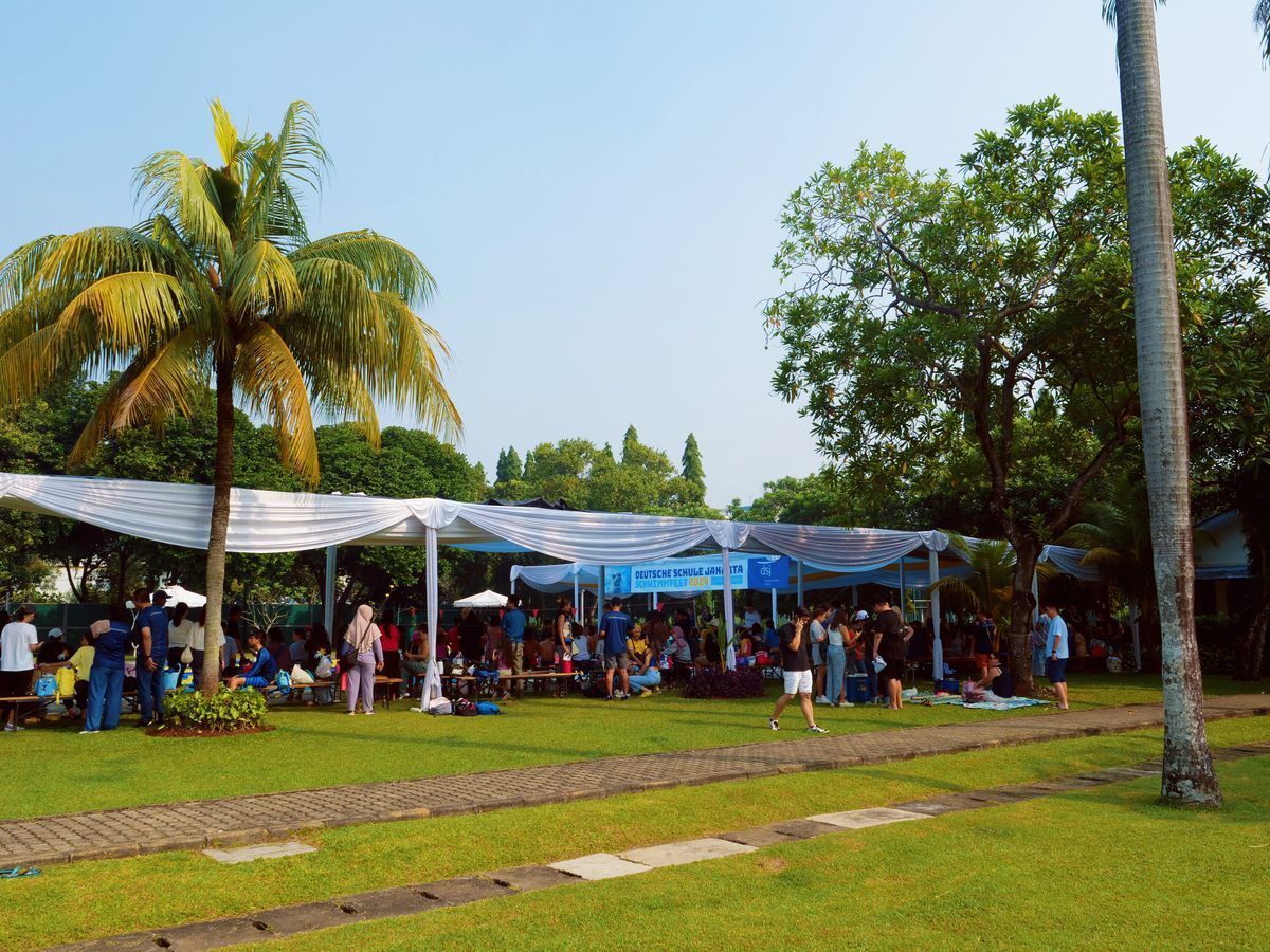 A group of people are gathered under a tent in a park