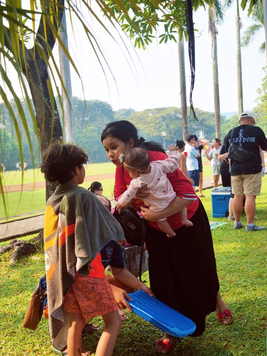 A woman is holding a baby in her arms in a park
