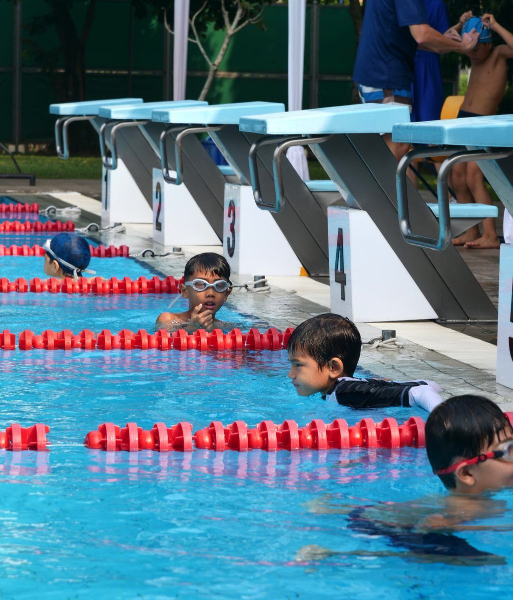 A group of young boys are swimming in a pool with lanes numbered 3 and 4