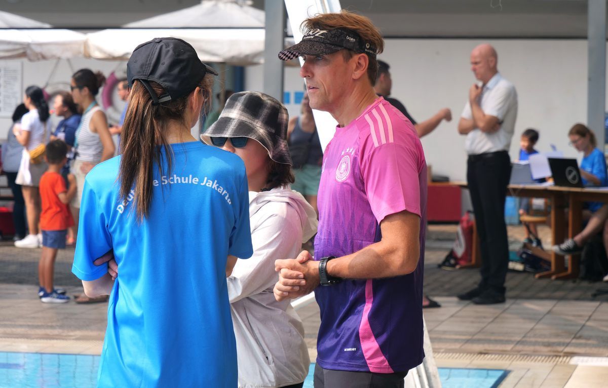 A man in a pink shirt is talking to a woman in a blue shirt