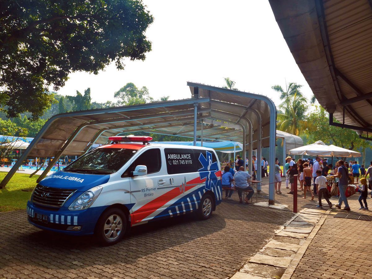 A blue and white ambulance is parked under a canopy