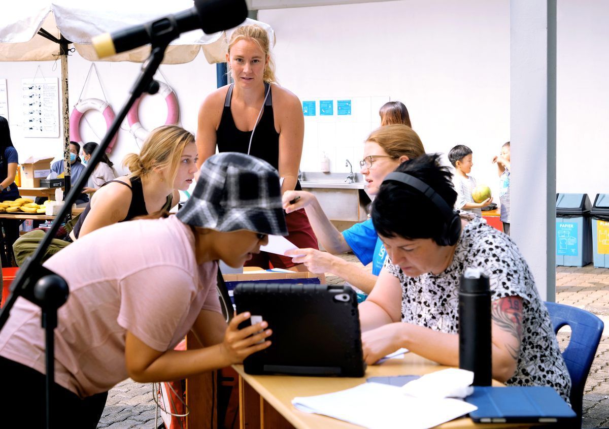 A group of people are sitting around a table looking at a tablet