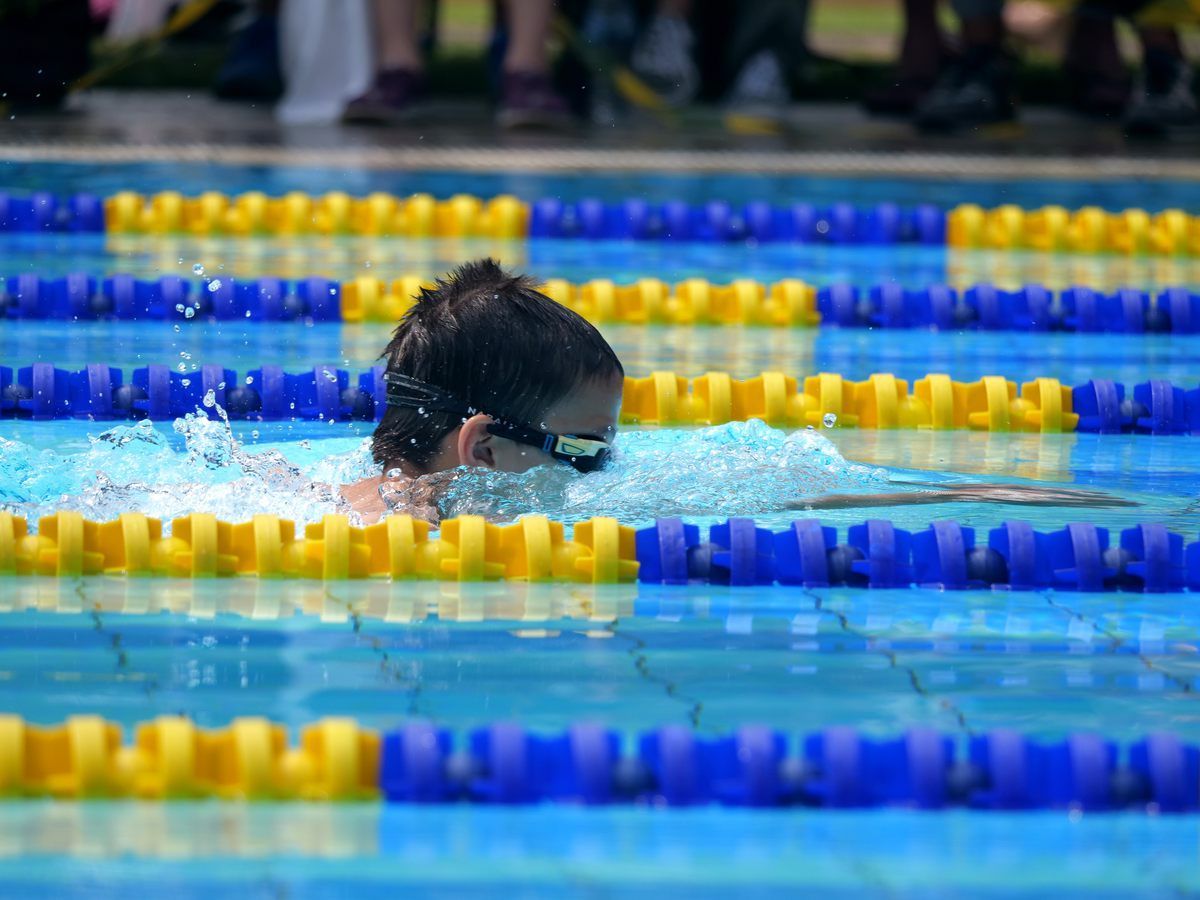 A woman is swimming in a swimming pool wearing goggles.