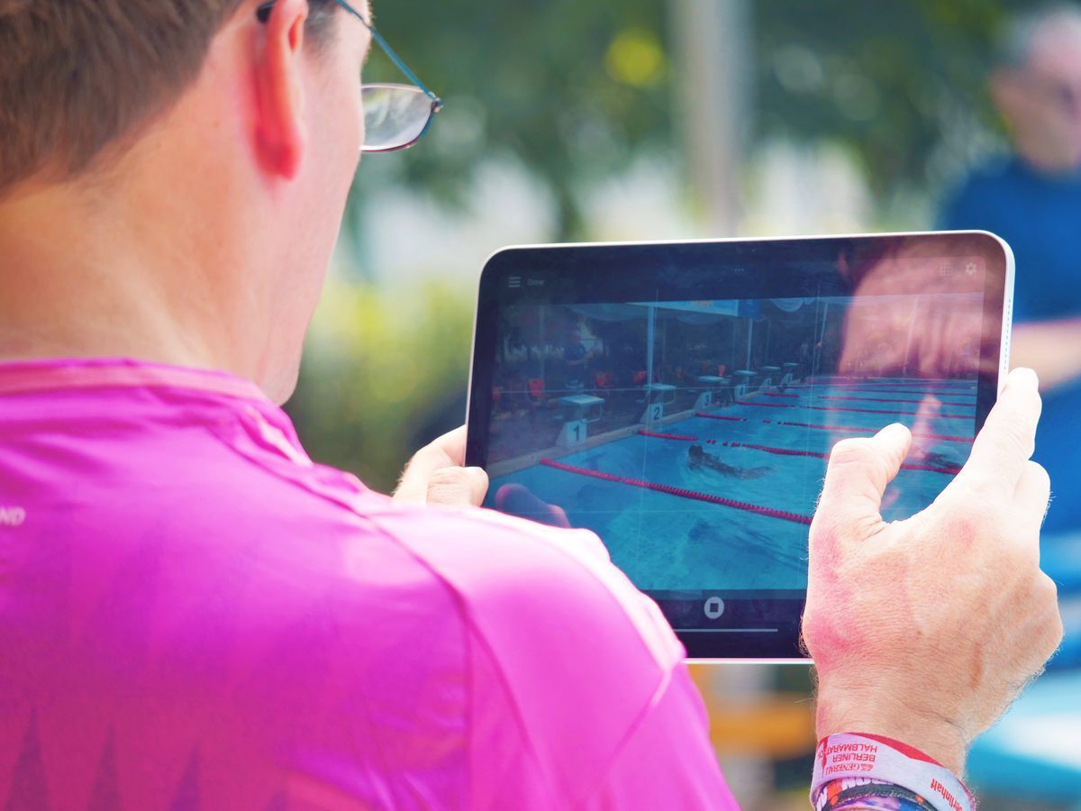 A man is taking a picture of a swimming pool on a tablet.