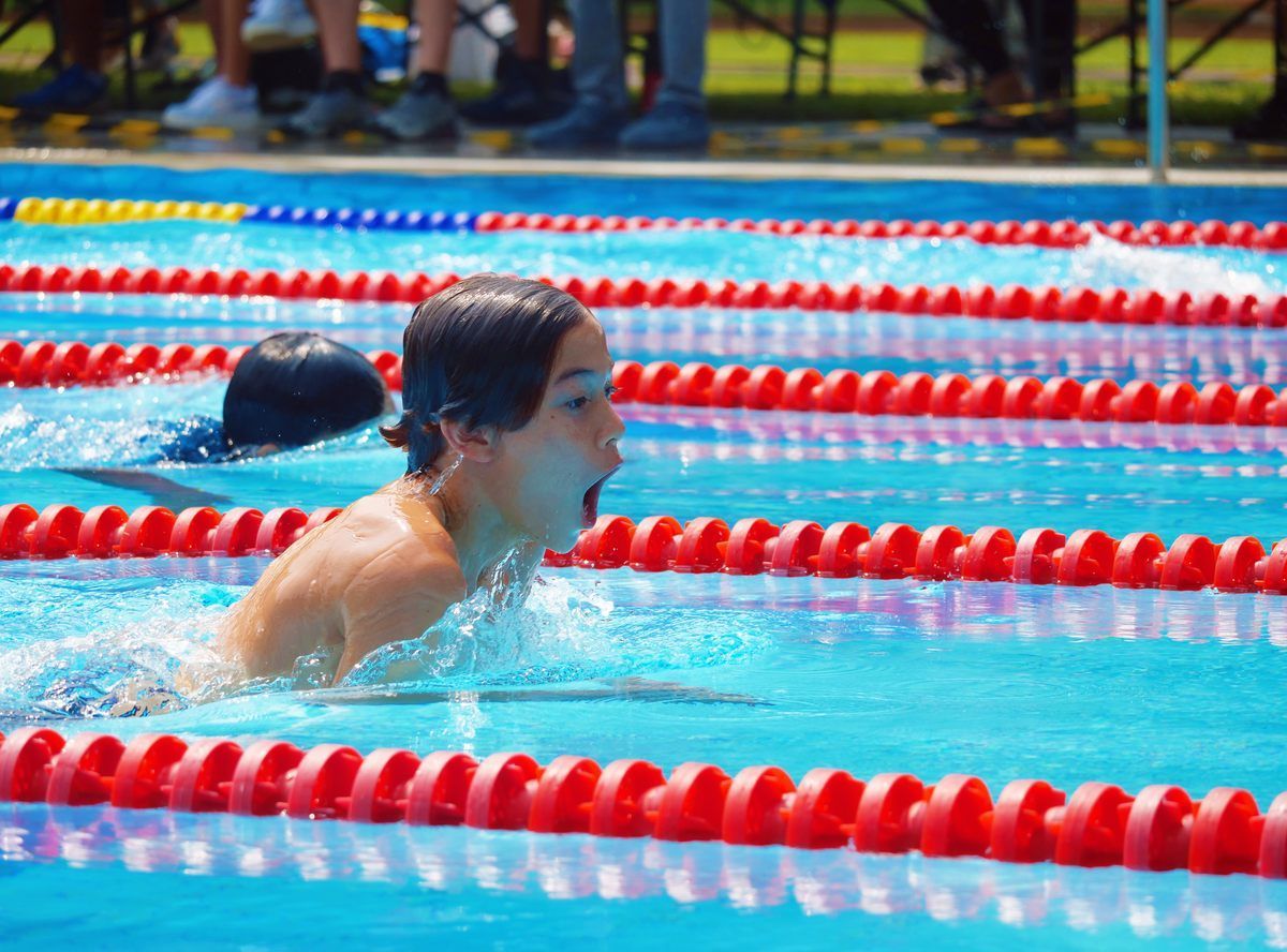 A boy is swimming in a swimming pool with red lanes.