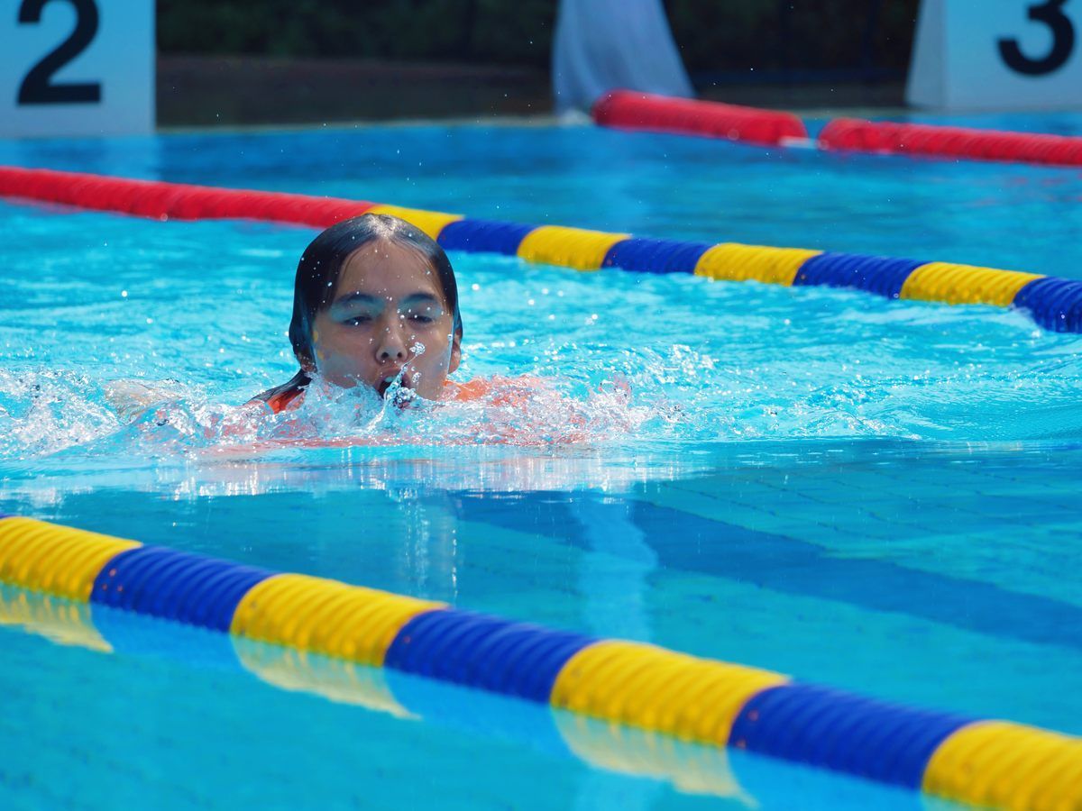 A young girl is swimming in a swimming pool.