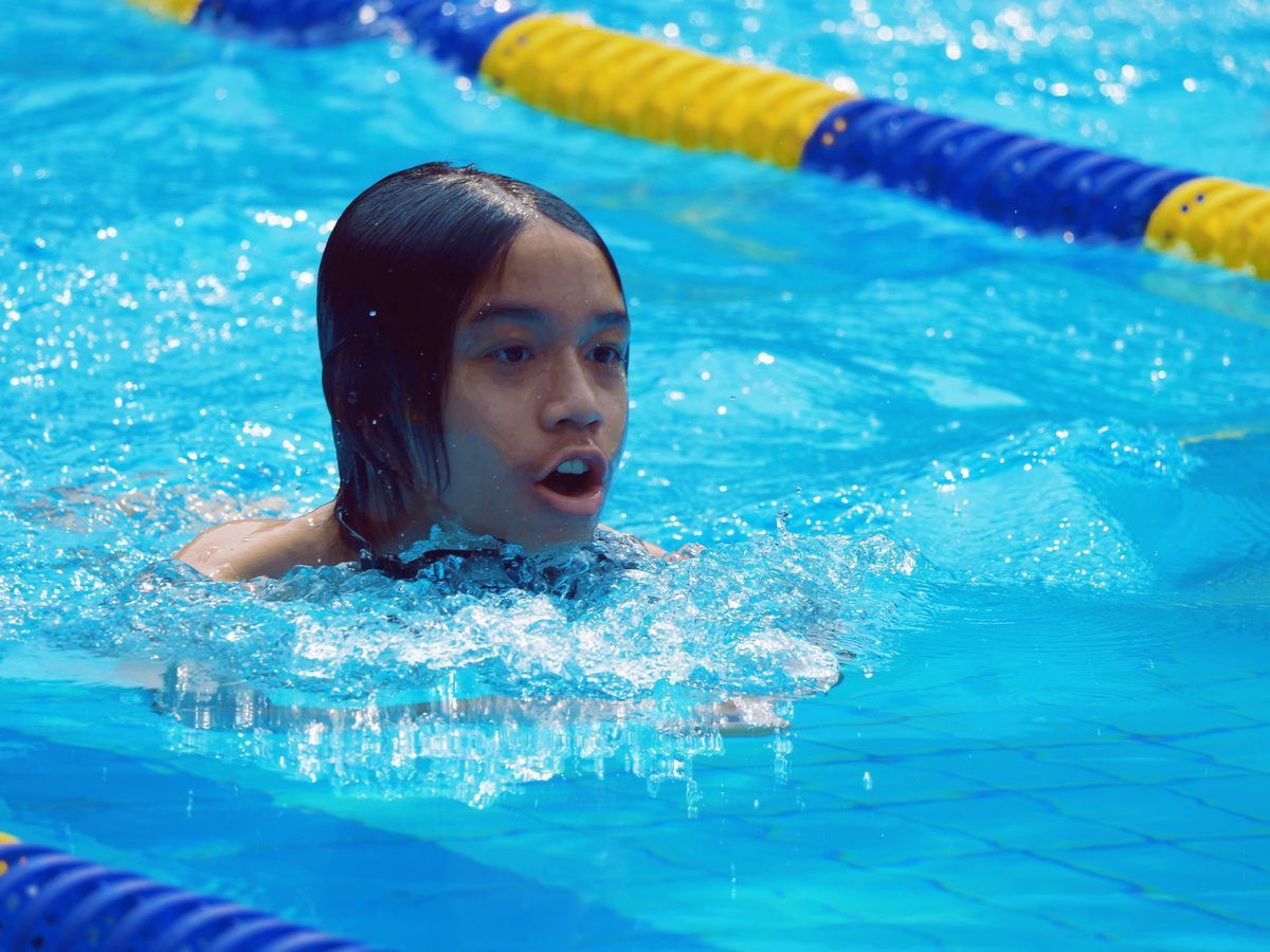 A young girl is swimming in a swimming pool.