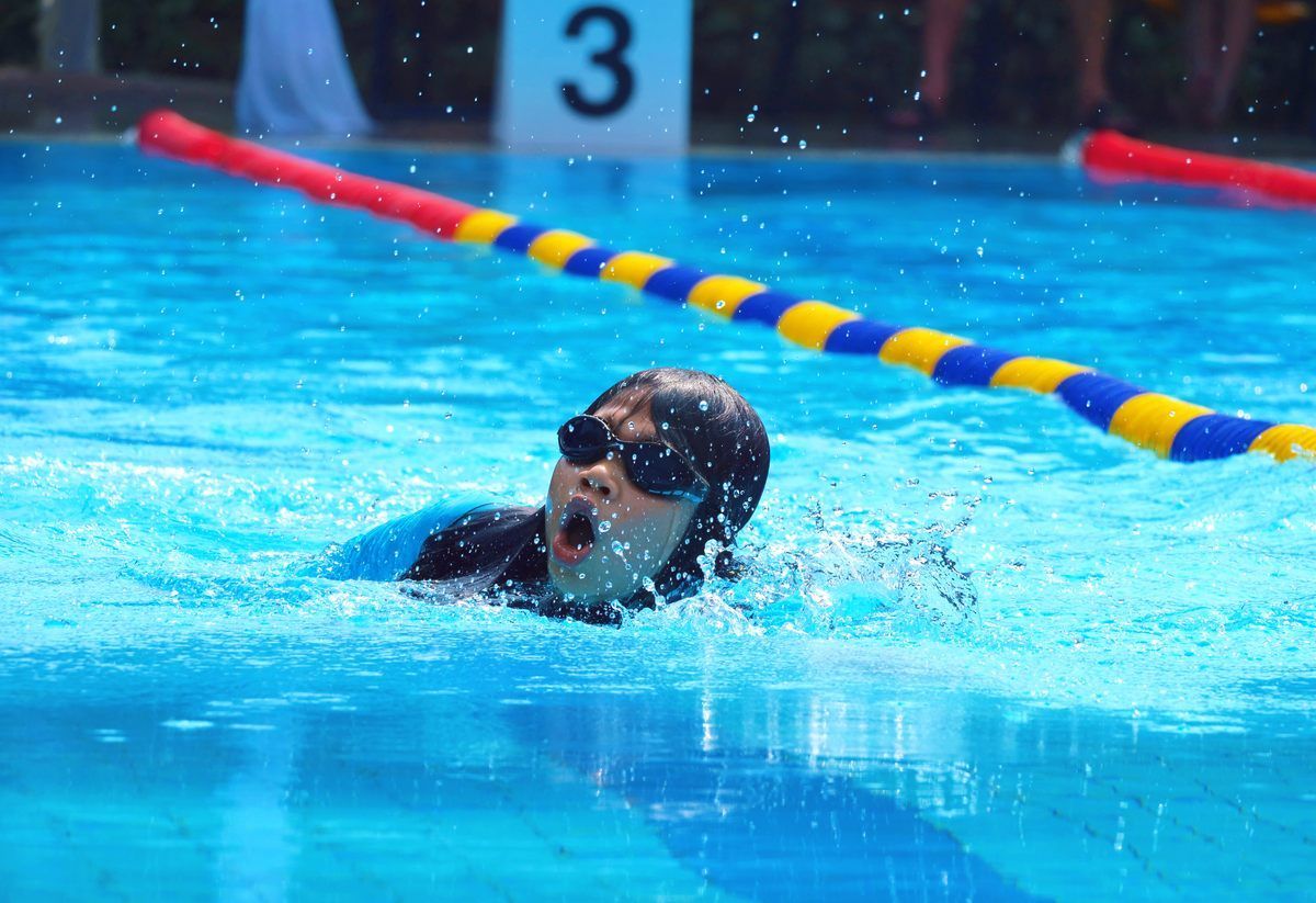 A person is swimming in a pool with the number 3 in the background