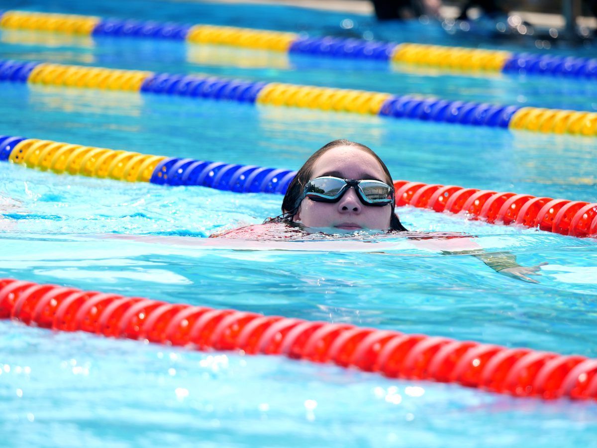 A woman wearing goggles is swimming in a swimming pool.