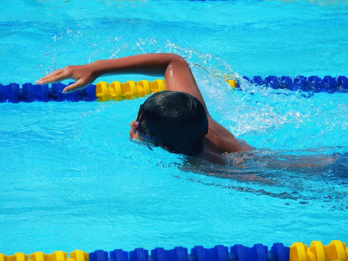 A young boy is swimming in a swimming pool.