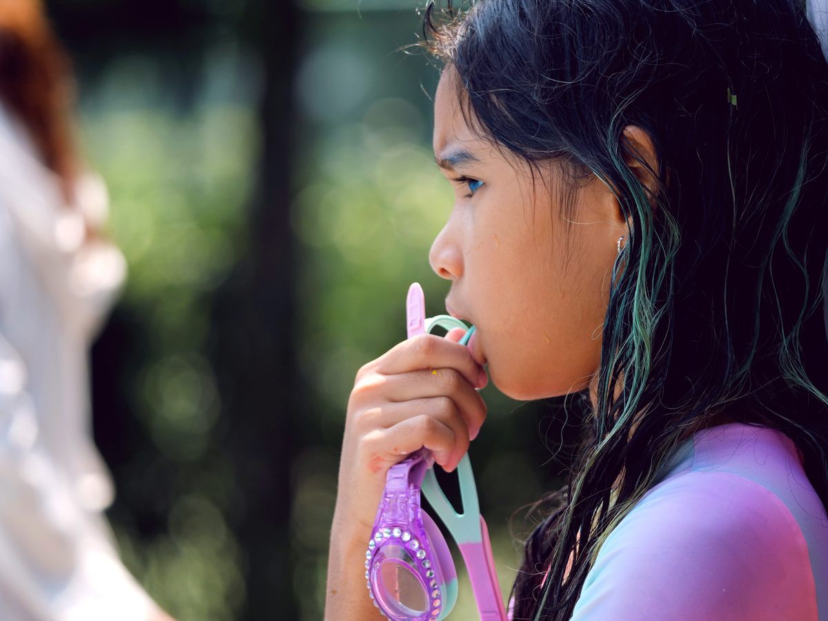 A young girl is blowing soap bubbles in a park.