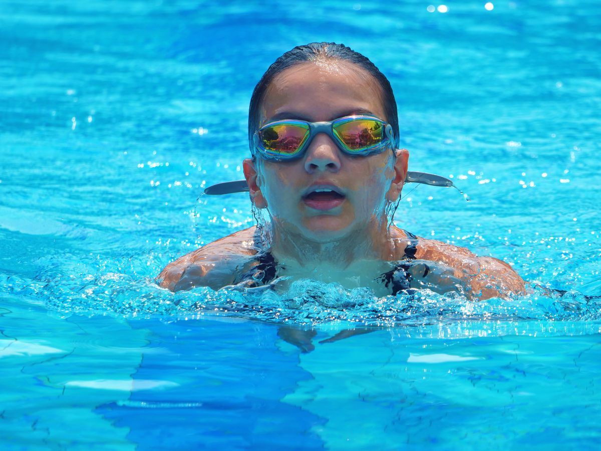 A woman wearing goggles is swimming in a pool.