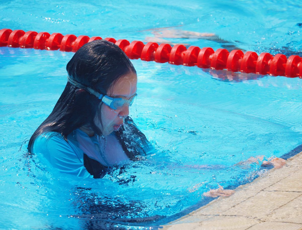A woman wearing goggles is swimming in a pool.