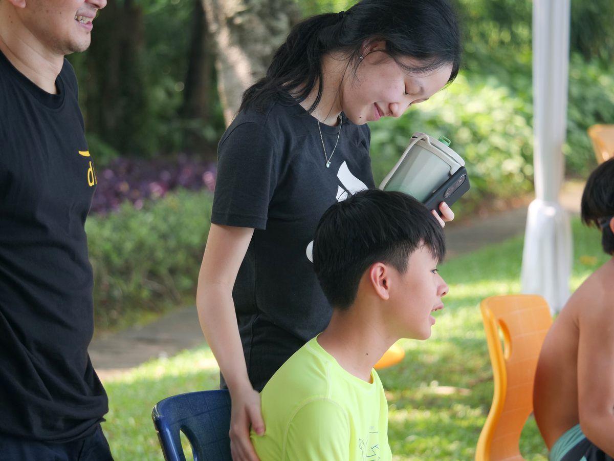 A woman in a black adidas shirt stands next to a boy in a green shirt