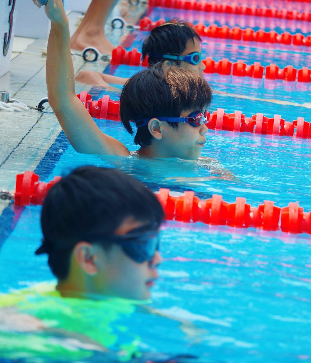 A group of young boys are swimming in a pool