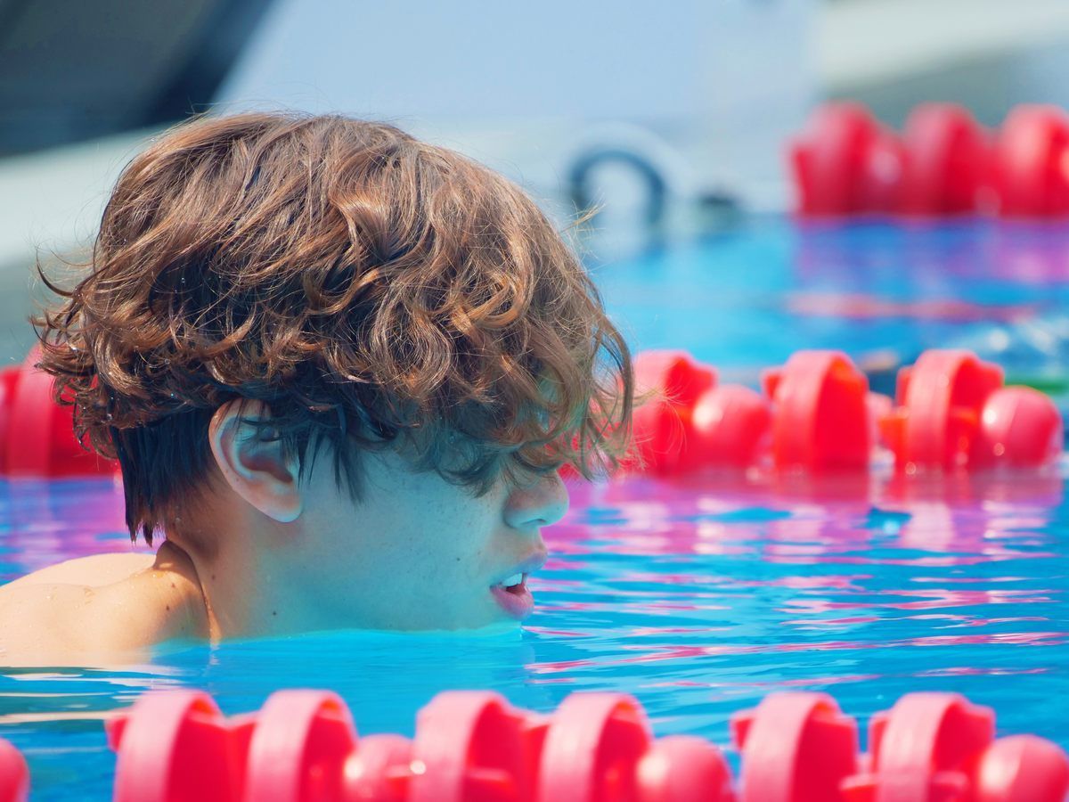 A young boy is swimming in a pool with red lanes