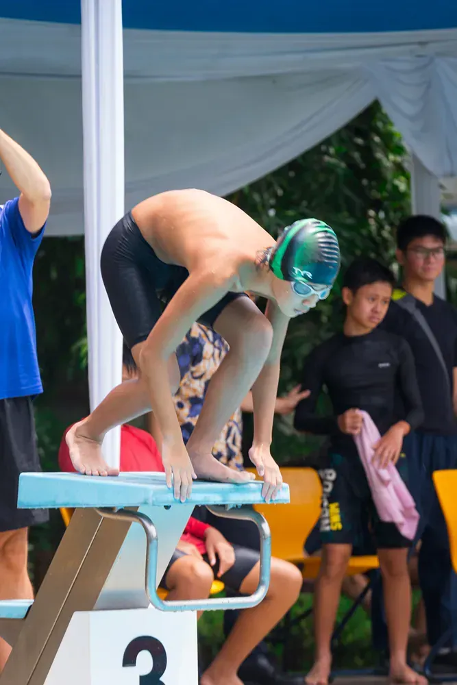 A young boy wearing goggles is swimming in a swimming pool.