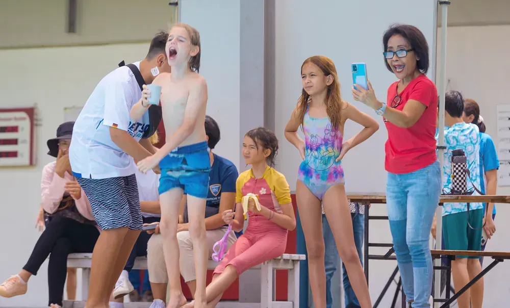 A group of people are standing around a swimming pool.