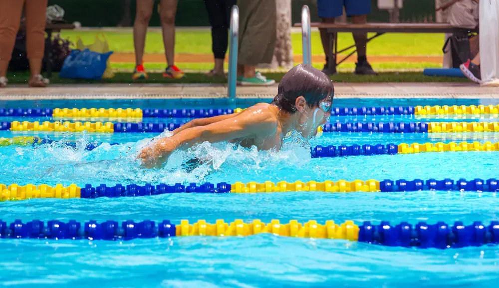 A young boy is swimming in a swimming pool.