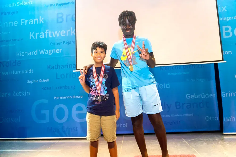 A man and a boy are standing next to each other holding medals