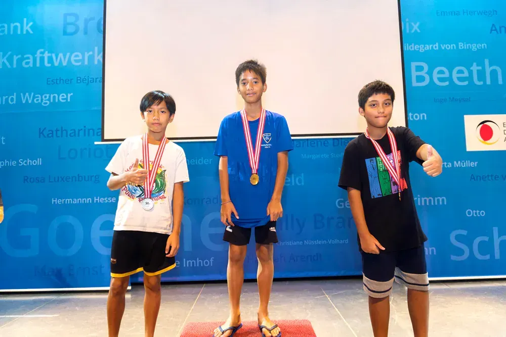 Three young boys are standing on a podium with medals around their necks.