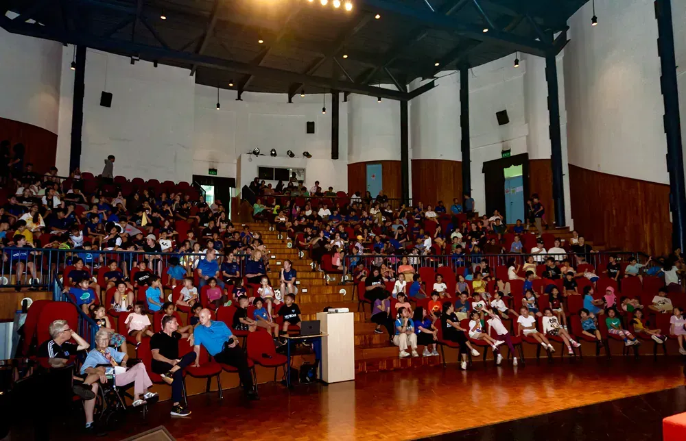 A large auditorium filled with people sitting in red seats