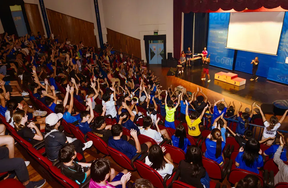 A large group of people are sitting in an auditorium watching a performance.