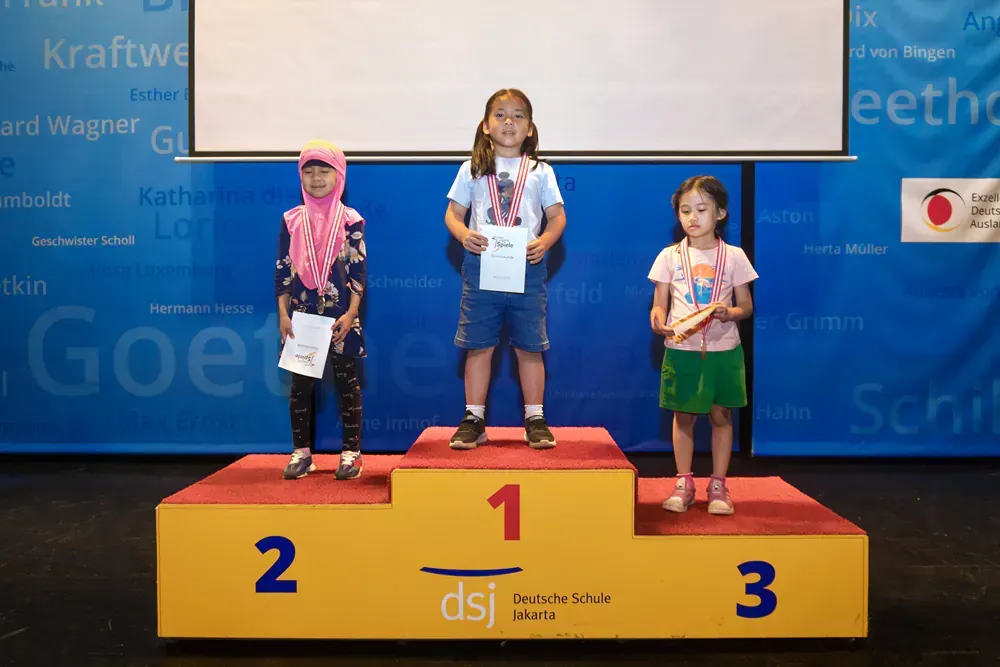 Three young girls are standing on a podium with the number 1 2 and 3 on it