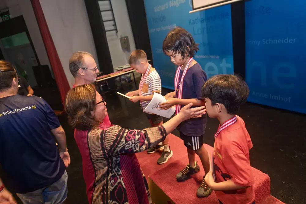 A woman is giving a medal to a young boy