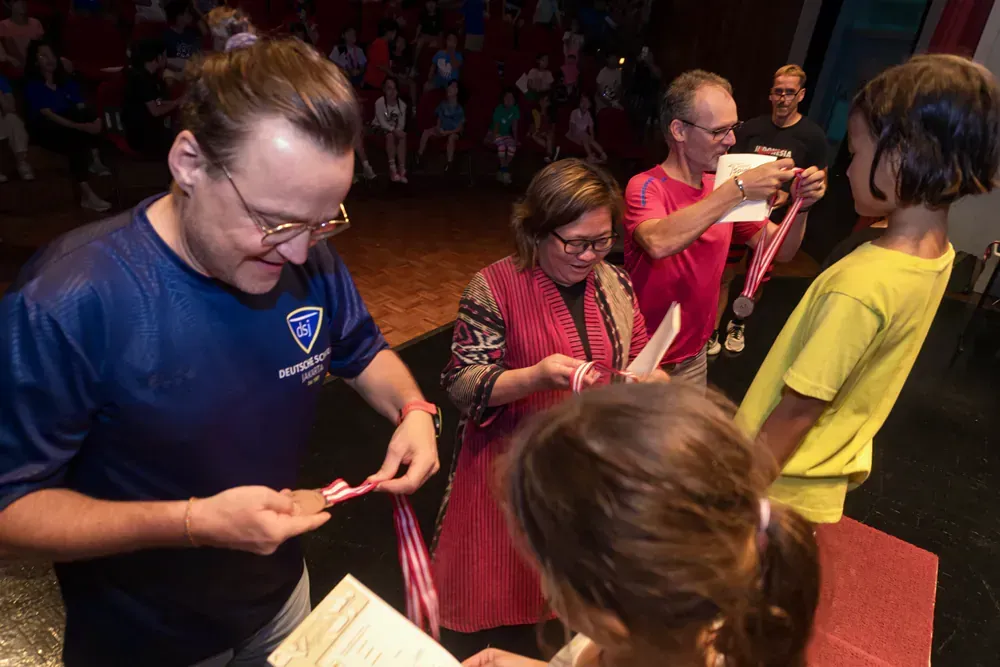 A group of people are standing around a table holding medals.