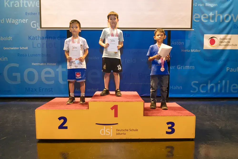 Three young boys standing on a podium with the number 1 on it