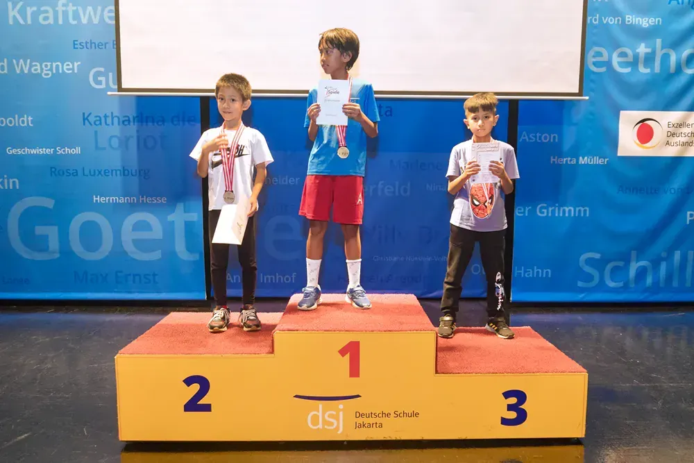 Three young boys stand on a podium with the number 1 on it